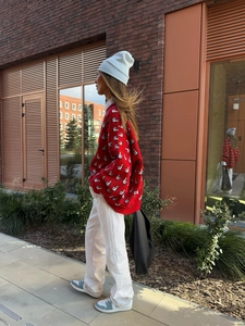 Détail d'un pull rouge oversize avec motif jacquard d'oiseau blanc dans un style urbain