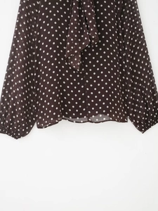 Dettaglio camicia in chiffon marrone a pois con scollo a fiocco e polsini elastici
