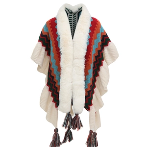 Detail of knit shawl featuring faux fur collar and colorful wave pattern with tassels