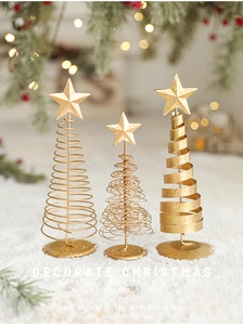 Three-piece set of gold iron mini Christmas tree ornaments on snow with warm lights
