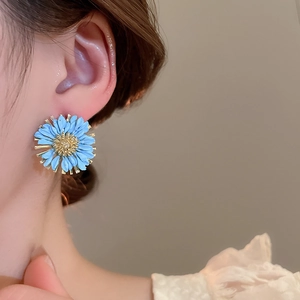 Macro detail of blue daisy flower earring with gold core on a model side view