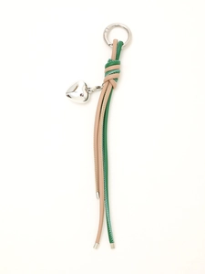 Detail of hand-woven beige and green leather cords with a silver heart pendant and metal ring