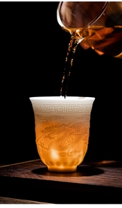 Detail of relief dragon pattern on white suet jade porcelain teacup with backlighting