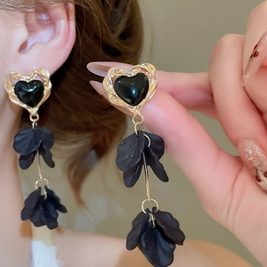 Detail of long heart earrings with golden wavy edges and black petal tassels