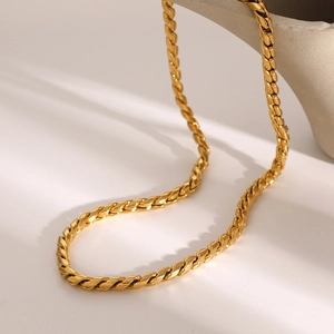 Macro view of golden link chain texture draped over minimalist ceramic dish