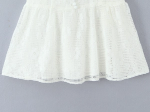 Détail du tissu en dentelle florale blanche avec bouton assorti sur la robe