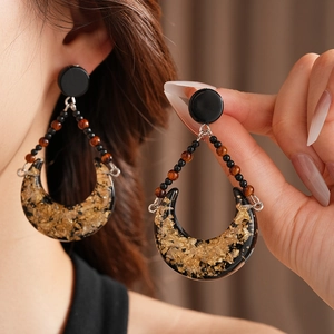 Detail showing vintage resin crescent earrings with gold leaf and beads worn by a model