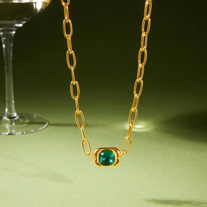 Luxurious gold chain necklace featuring a green cushion-cut gemstone pendant on green background