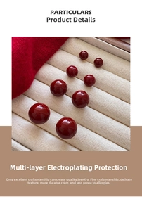 Macro shot of red enamel spherical earrings with high-shine plating on a jewelry tray