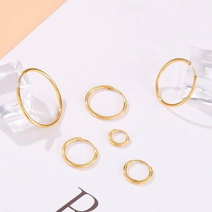 Detailed view of various sizes of golden hoop earrings on a decorative prop background