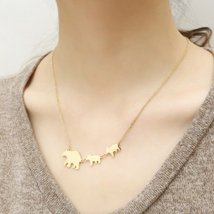 Detailed view of three golden bear pendants on a stainless steel necklace worn by a model
