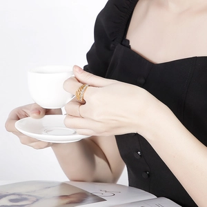 Golden vintage stainless steel ring with rhinestones on hand with coffee and magazine