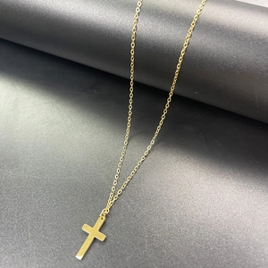 Dettaglio della collana a croce in acciaio inossidabile dorato su base industriale scura