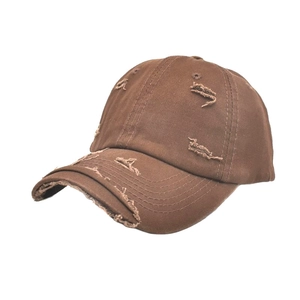Detail of distressed brown cotton baseball cap with vintage frayed holes and worn-out style
