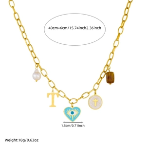 Collier à maillons dorés avec breloques cœur, croix et perle sur fond blanc éclatant