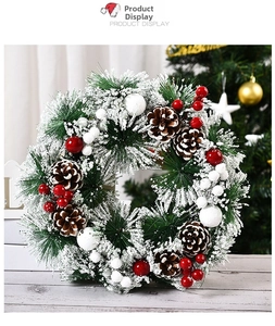 Primer plano de una corona de Navidad nevada con bayas rojas y piñas naturales.