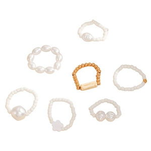 Detail of 7-piece pearl and gold bead ring set with geometric turquoise and floral accents