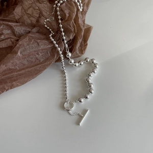 Close-up of 925 silver beaded chain necklace with T-bar clasp on aesthetic brown background