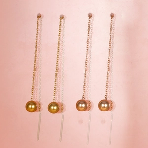 Detail of gold and rose gold long chain earrings with polished bead drop pendants