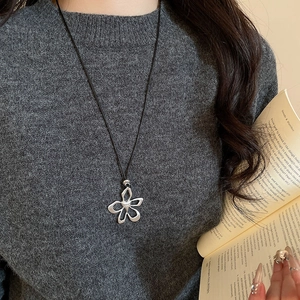 Close-up of a silver hollow flower pendant with a black leather cord necklace for women