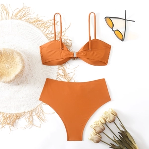 Flat lay of terracotta bikini set with metal buckle detail, sun hat, and sunglasses