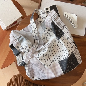 Détail d'un sac cabas en coton patchwork avec motifs floraux et carreaux sur table