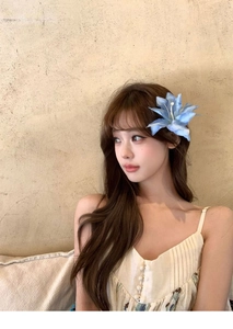 Light blue fabric flower hair clip accessory worn on long hair for an elegant look