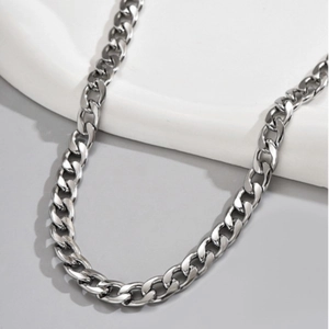 Polished silver stainless steel Cuban link chain necklace for men on minimalist white stand