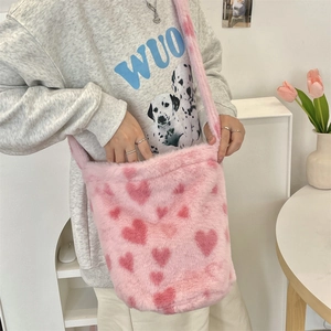 Detail of soft pink plush bucket bag with red heart pattern and long furry strap