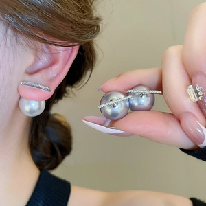 Detail view of large pearl earrings with crystal-inlaid curved metal bar on the ear