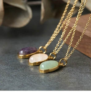 Macro detail of three oval aventurine and gemstone pendants on 18K gold plated chains