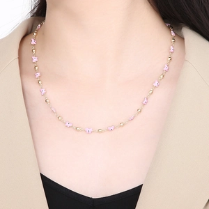 Close-up of golden chain necklace with pink butterfly beads and small gold accents