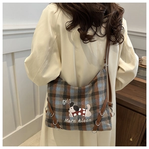 Detail of plaid tweed shoulder bag with cartoon dog pattern and leather strap