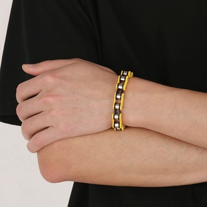 Detail shot of yellow and silver motorcycle chain bracelet on wrist with industrial design