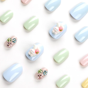 Short round macaron nails with 3D bunny and floral charms on a clean white background