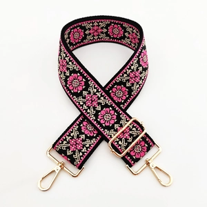 Detail of colorful jacquard wide bag strap with pink floral embroidery and gold metal hooks