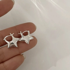 Minimalist silver pentagram star hoop earrings for women shown on hand for scale