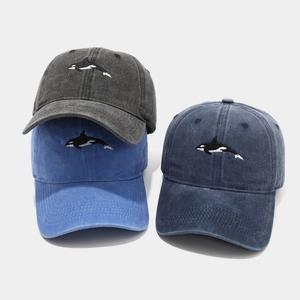 Detailed embroidery of an orca on vintage washed cotton baseball caps in multiple colors