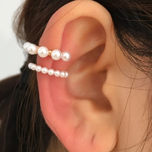 Detail of gold pearl ear cuff set showing different sizes worn on the ear cartilage