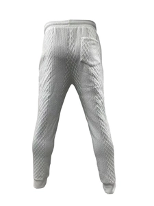 Detail view of white knitted jogger pants featuring 3D jacquard texture and elastic waist