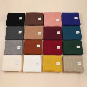 Flat lay of colorful striped knit shawls in sixteen different vibrant color options