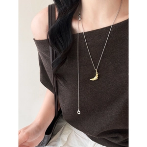 Detail of moon pendant with gold texture on silver chain against a knit sweater