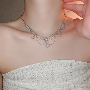 Détail du collier à pampilles multicouches avec perles argentées et une perle blanche centrale