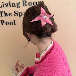 Pink star-shaped acetate hair claw clip with heart rhinestone shown in a stylish updo