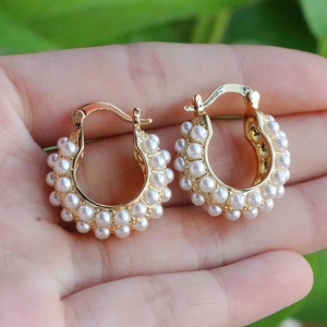 Elegant French style gold hoop earrings with white pearls shown in hand for size context