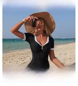 Detail of slimming black and white tankini with V-neck trim on a sunny beach setting
