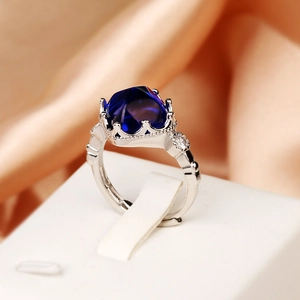Macro shot of silver ring with large blue gemstone in a crown setting and side diamonds