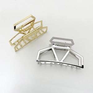 Detail view of large geometric hollow metal hair claws in polished gold and silver finishes