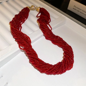 Detail of red multilayer beaded necklace with elegant twisted strands and golden metal clasp