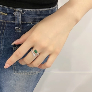 Detailed close-up of a silver ring with square green gemstone worn on index finger
